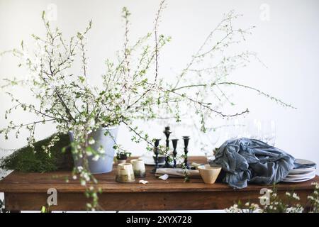 Blumen, Gläser und Geschirr auf einem Tisch für das Abendessen mit Kerzen Stockfoto