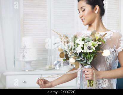 Ungewöhnliche Hochzeit Bouquet mit Ranunkeln, Freesien, Rosen und weißen Anemone im retro-Stil in Händen einer Braut Stockfoto