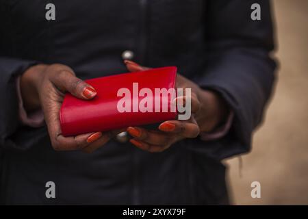 Die Frau hält die rote Brieftasche in der Hand Stockfoto