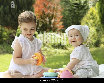 Zwei spielende kleine Schwestern im Sommergarten Stockfoto