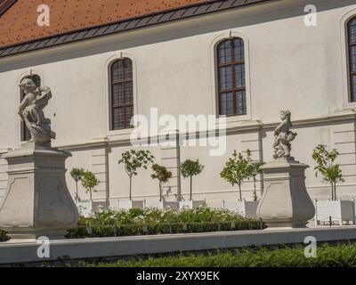 Zwei barocke Statuen in einem gepflegten Garten vor einem historischen Gebäude unter sonnigem Himmel, bratislava, slowakei Stockfoto