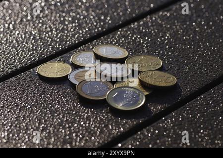 Euro, Münzen, Kleingeld, Glühen, verschiedene Cent- und Euro-Münzen liegen auf einem Tisch vor einem verschwommenen, glitzernden Hintergrund Stockfoto