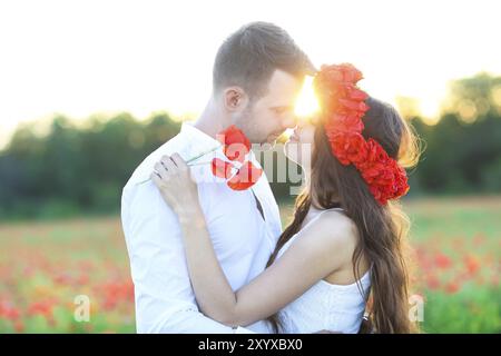 Junges Paar in Liebe küssen und umarmen im Mohnfeld Stockfoto
