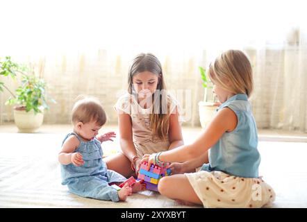 Drei niedliche Mädchen spielen zusammen in Innenräumen Stockfoto