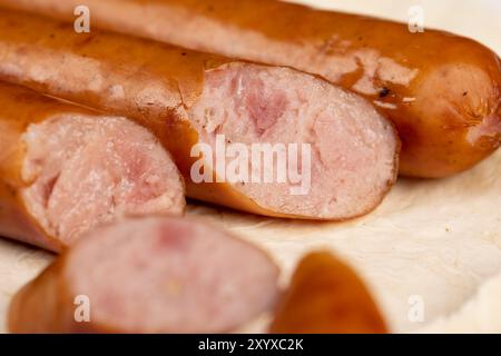 Schweinefleischwürste auf einer Weizentortilla schneiden, Nahaufnahme von dünnen Schweinefleischwürsten im Ofen gebraten Stockfoto