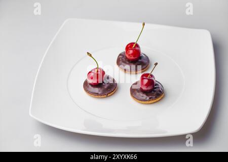 Drei Kirschen auf drei Schokoladenkeksen Stockfoto