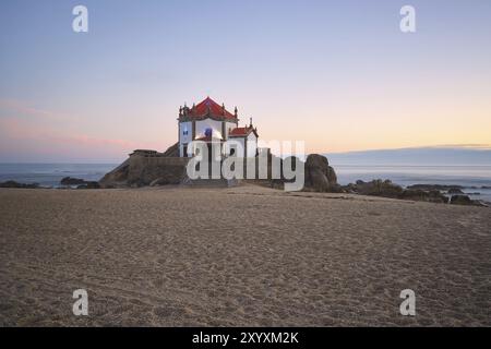 Schöne Kapelle am Strand Capela do Senhor da Pedra bei Sonnenuntergang in Miramar, in Portugal Stockfoto