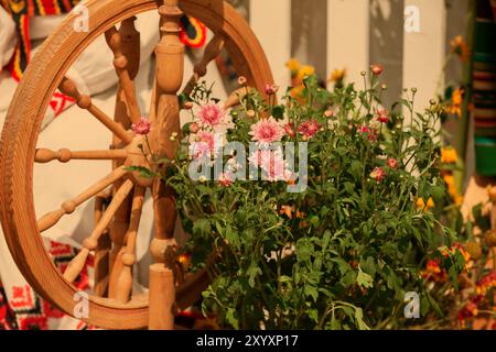 Rustikales Vintage Stillleben mit Chrysanthemen und einem alten Spinnrad. Stockfoto