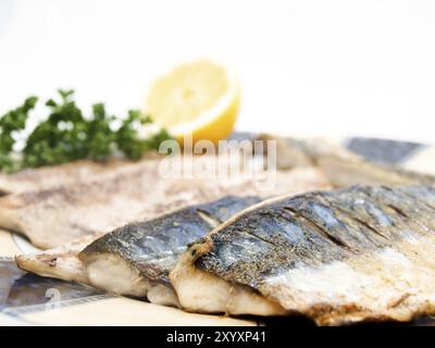 Gebratene Makrelenfilets auf bunten Teller mit einer halben Zitrone und Petersilie Stockfoto