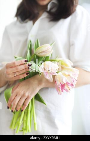 Schöne junge Frau hält eine Reihe von zarten Frühling rosa Tulpen vor ihr. Nahaufnahme Stockfoto