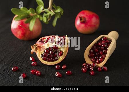 Reifer Granatapfel Obst und bailer mit Samen im Inneren über einem schwarzen strukturierten Hintergrund Stockfoto