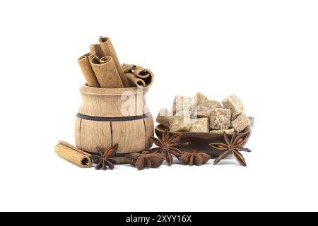 Holzschale gefüllt mit Zimtstangen, Sternanis und braunen Zuckerwürfeln in einer Holzschale isoliert auf weißem Hintergrund Stockfoto