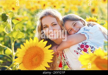 Glückliche Mutter und ihrer kleinen Tochter in dem Sonnenblumenfeld. Sommerspaß Stockfoto