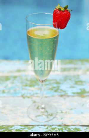 Glas Champagner mit Erdbeeren auf blauem Hintergrund Sommer-Pool-party Stockfoto