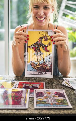 Tarot-Leser, der die riesige Tarot-Karte fröhlich hält, während er lacht Stockfoto