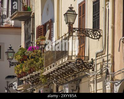 Nahaufnahme eines eisernen Balkons mit blühenden Blumen und altmodischen Laternen, palermo, sizilien, mittelmeer, italien Stockfoto