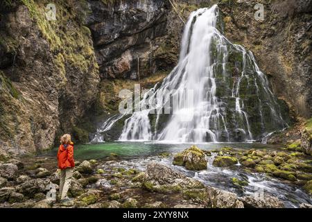 Ein Wanderer am Gollinger Wasserfall (Schwarzbachfall, Schwarzenbachfall) im Herbst. Felsen mit Moos. Tennengau, Salzburger Land, Oberösterreich, Österreich Stockfoto