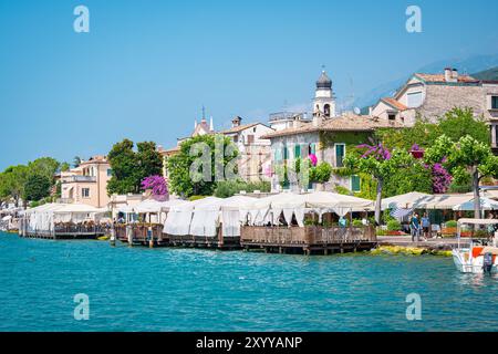 Malerischer Blick auf die Küstenstadt Torri del Benaco am Gardasee, Italien mit vielen Touristenrestaurants Stockfoto