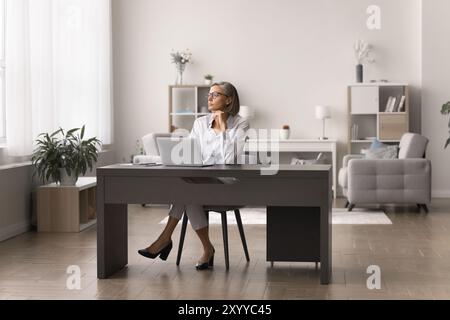 Reife Geschäftsfrau sitzt am Schreibtisch mit Computer im Heimbüro Stockfoto