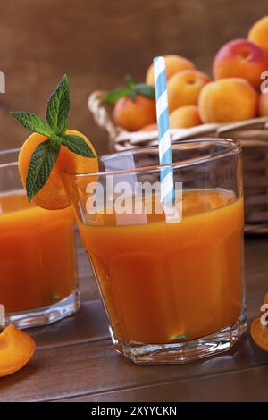 Großaufnahme von frischem Saft mit Aprikosen in einem Korb auf hölzernem Hintergrund Stockfoto