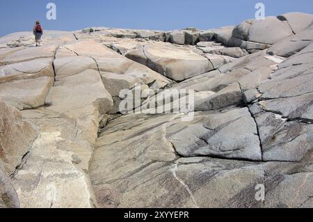 Frau, die die Felsen in der Nähe von Peggy's Cove, Nova Scotia, Kanada, Nordamerika klettert Stockfoto