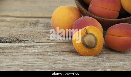 Sammlung von Reifen ganzen Aprikosen und einer in zwei Hälften geschnitten, um den rustikalen Holztisch im Inneren zu enthüllen Stockfoto