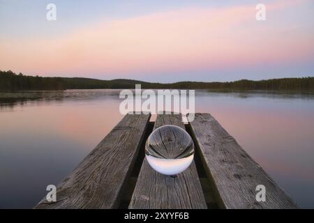 Glasball auf einem hölzernen Pier an einem schwedischen See zur Abendstunde. Natur aus Skandinavien Stockfoto