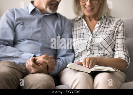 Ein älteres Paar liest ein Buch auf dem Sofa und sieht aus der Nähe Stockfoto