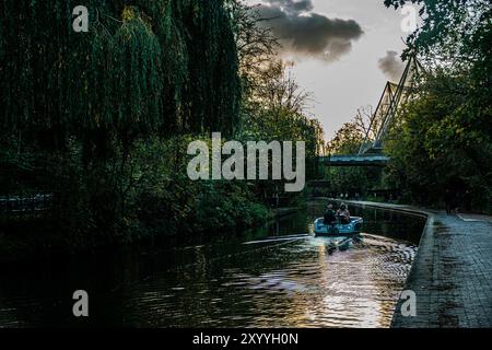 Eine ruhige Bootsfahrt entlang des Regent's Canal in der Abenddämmerung, umgeben von üppigem Grün und sanften Reflexen, bietet einen ruhigen Rückzugsort im Herzen von London. Stockfoto