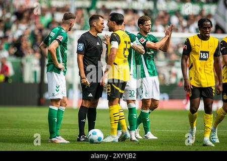 31.08.2024, WESERSTADION, GER, 1.FBL, SV Werder Bremen vs Borussia Dortmund im Bild Emre CAN (Borussia Dortmund #23) beschwert sich bei Schiedsrichter/Schiedsrichter Robert Hartmann, nachdem Niklas Süle/Suele (Borussia Dortmund #25) Gelb sah, Foto © nordphoto GmbH/Rauch Gemäß den Vorgaben der DFL Deutsche Fußball Liga bzw. Des DFB Deutscher Fußball-Bund ist es untersagt, in dem Stadion und/oder vom Spiel angefertigte Fotoaufnahmen in Form von Sequenzbildern und/oder videoähnlichen Fotostrecken zu verwerten bzw. Verwerten zu lassen. Stockfoto