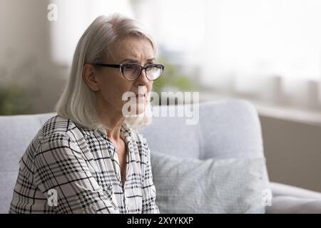 Reife Frau, tief in traurigen Gedanken, sitzt allein zu Hause Stockfoto