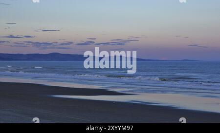 Sonnenuntergangsszene an einem Strand in der Nähe von Christchurch, Neuseeland. Pastellfarbene Landschaft. Waikuku Beach. Rosa Himmel Stockfoto