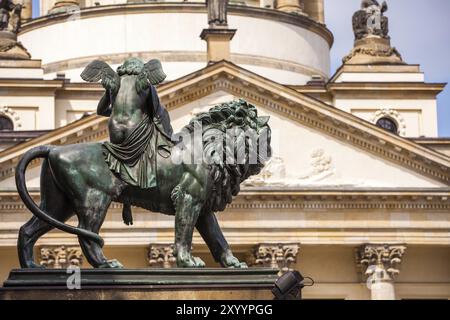 Statue eines Engels, der auf einem Löwen reitet und Harfe spielt, mit der französischen Kathedrale im Hintergrund Stockfoto