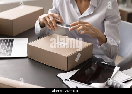 Versandprozess von Paketen mit mobiler Barcode-Anwendung bei Frauen Stockfoto