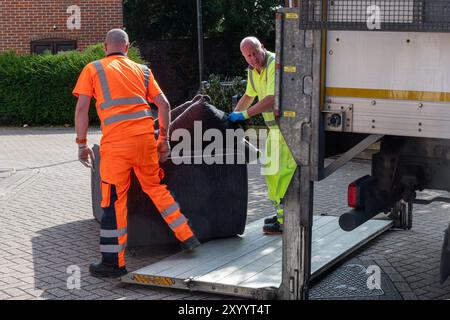 Zwei männliche gemeindearbeiter sammeln weggeworfenes Sofa oder Sofa, Sperrmüll-Entsorgungs- und Sammelservice, England, Großbritannien Stockfoto