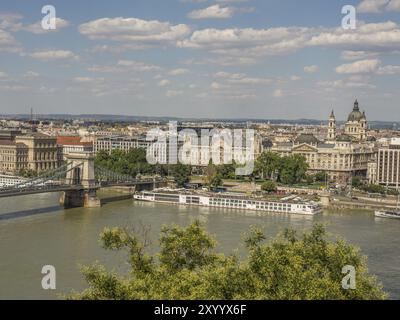 Panoramablick auf eine Stadt mit einer Brücke über einen Fluss und prominenten Gebäuden im Hintergrund unter einem bewölkten Himmel, budapest, donau, ungarn Stockfoto