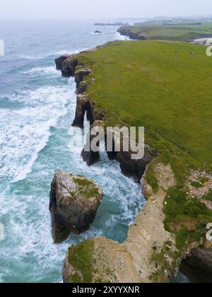 Beeindruckende Aussicht auf steile Klippen mit einzigartigen Felsformationen und einer üppigen grünen Landschaft, aus der Vogelperspektive, Praia das Catedrais, Playa de las Catedrales, Cat Stockfoto