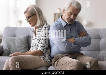 Unzufriedene, reife Ehepartner sitzen schweigend auf dem Sofa Stockfoto