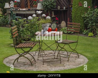 Metalltisch und zwei Stühle auf einer Steinplatte im Garten, dekoriert mit einer Büste und kleinen Lampen, borken, münsterland, deutschland Stockfoto