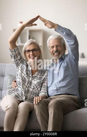 65er-Jahre-Paar, das Hände unter Köpfen mit Dachsymbol verbindet Stockfoto