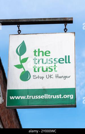 Das Trussell Trust-Schild vor einem Wohltätigkeitsladen mit dem Slogan Stop UK Hunger. Wohltätigkeitsorganisation, die Lebensmittelbanken unterstützt und Menschen in Krisensituationen helfen soll Stockfoto