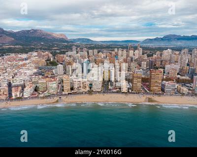 Luftdrohne aus Sicht der Stadt Benidorm. Berühmtes Reiseziel in der Provinz Alicante, Spanien. Wolkenkratzer, Berge im Hintergrund, Mediterranea Stockfoto
