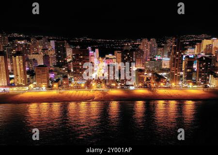 Skyline von Benidorm bei Nacht. Straßenlicht reflektiert im Wasser. Berühmtes Reiseziel im Süden Spaniens, Provinz Alicante. Wolkenkratzer. Stockfoto