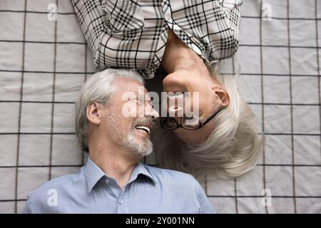 Liebevolles älteres Paar aus den 65ern, das auf dem Bett lag und von oben aus gesehen wurde Stockfoto
