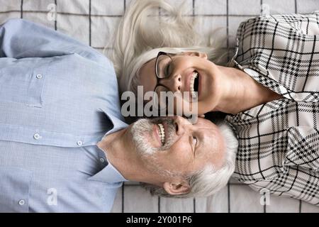 Die Ehepartner lachen und liegen auf frisch gewaschenen Laken auf dem Bett Stockfoto