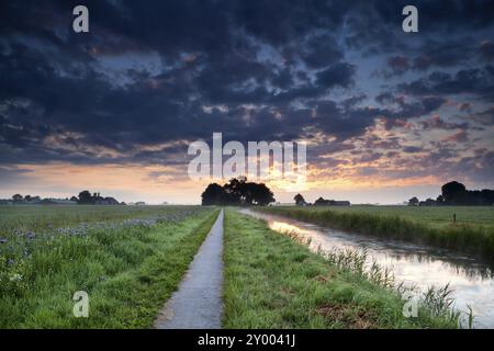 Dramatischer Sommersonnenaufgang über Ackerland mit Kanal und Feldern Stockfoto