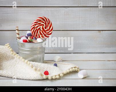 Bunte Bonbons in einen kleinen Eimer auf hölzernen Hintergrund mit Textfreiraum Stockfoto