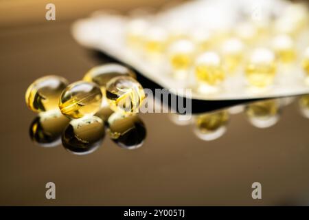 Gelbe transparente Kapseln von Vitamin D und Fischöl Omega-3, in einer sichtbaren Blisterpackung dargestellt, die Nahrungsergänzungsmittel für Gesundheit und Gesundheit betont Stockfoto