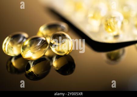 Nahaufnahme von gelben, transparenten Kapseln mit Vitamin D und Omega-3-Fischöl-Ergänzungen auf einer reflektierenden Oberfläche, ideal für Heilung Stockfoto