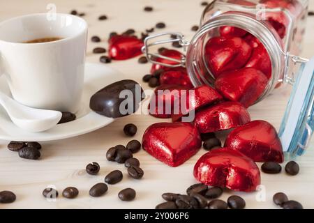 Rot Schokolade Herzen in einem Glas und einer Espressomaschine mit Kaffeebohnen auf einem Tisch Stockfoto